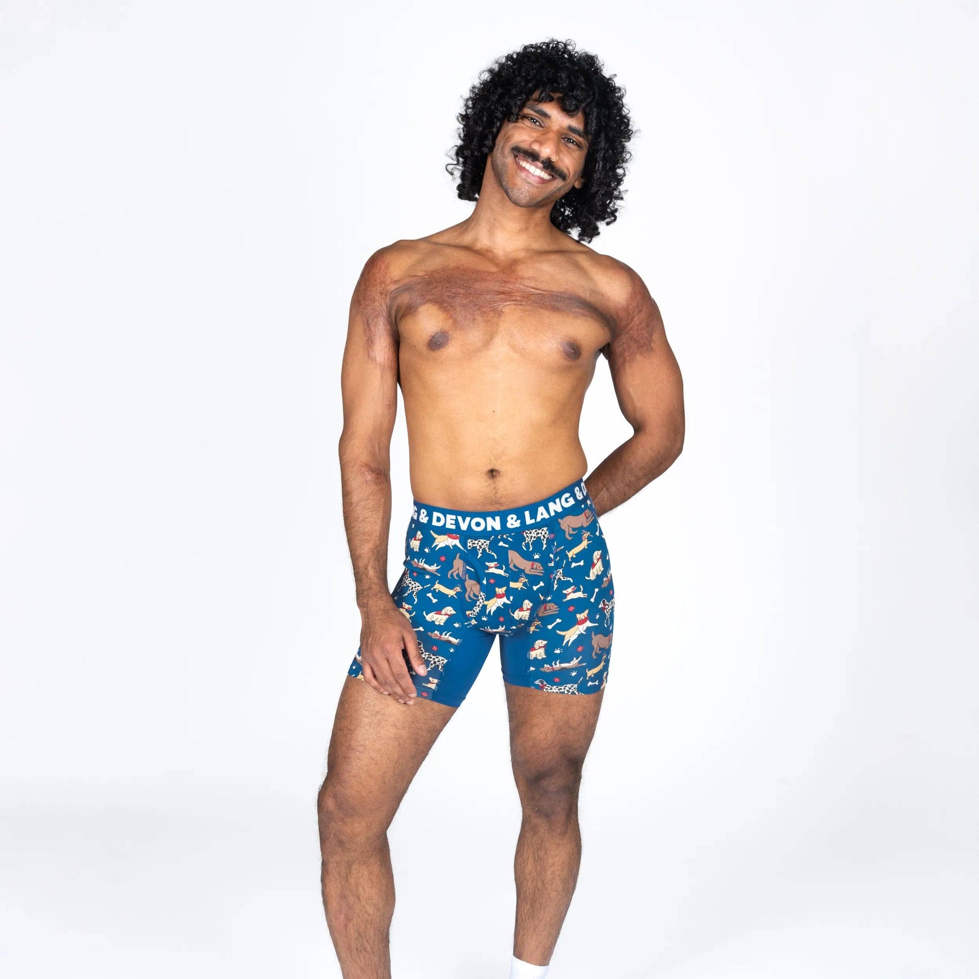 A man modeling blue boxer briefs with a white and orange animal print, featuring the waistband text 'DEVON & LANG'.