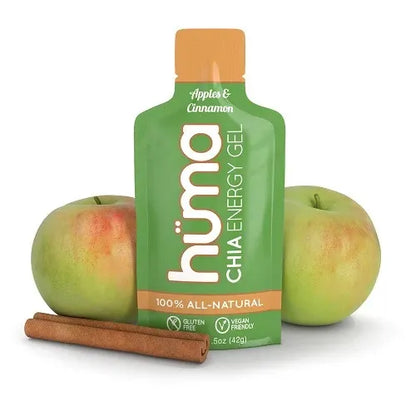 A green Huma Chia Energy Gel pouch with an orange cap, styled with two green apples and a cinnamon stick on a white background.