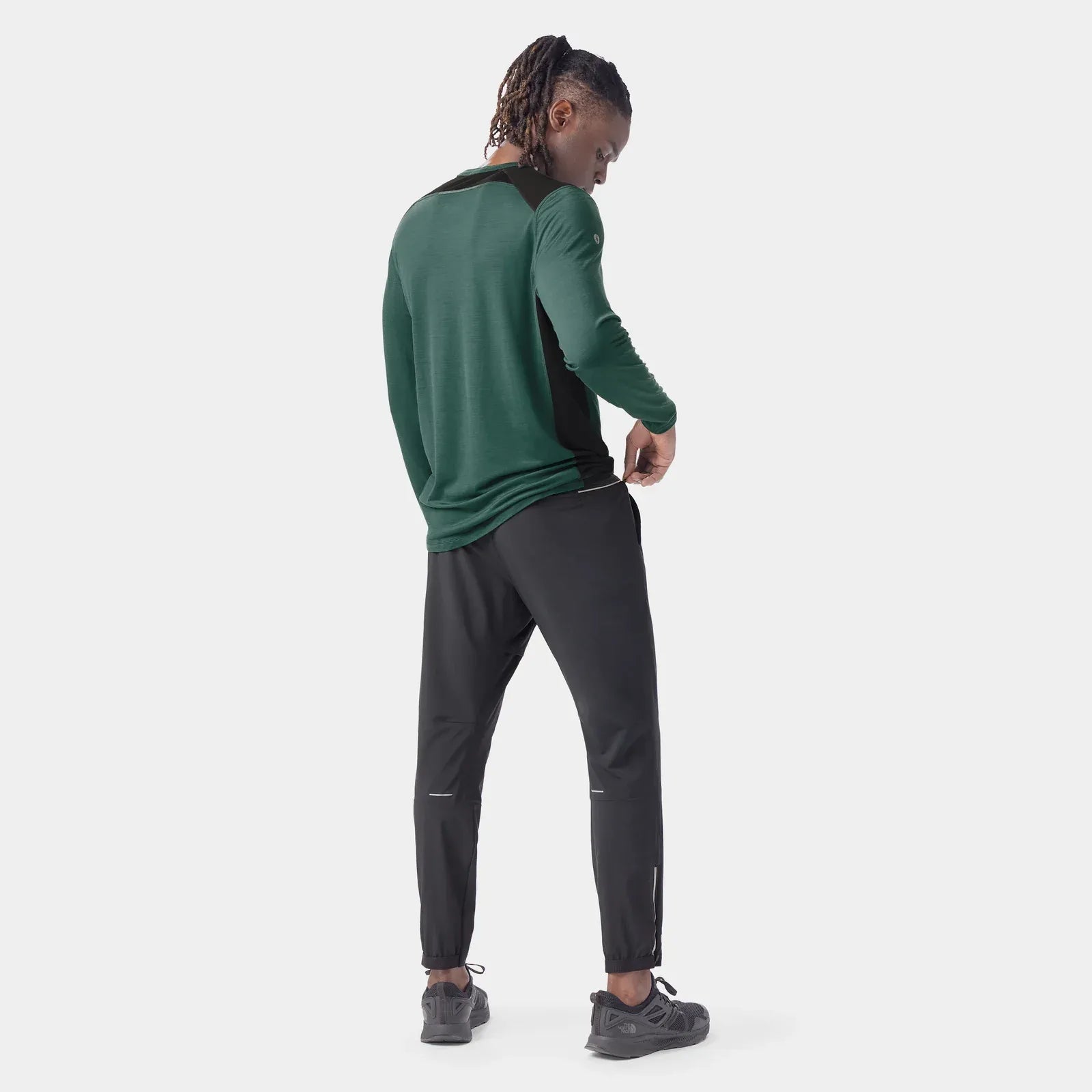 Person wearing a green jacket and Smartwool Active Running pants  on a white background