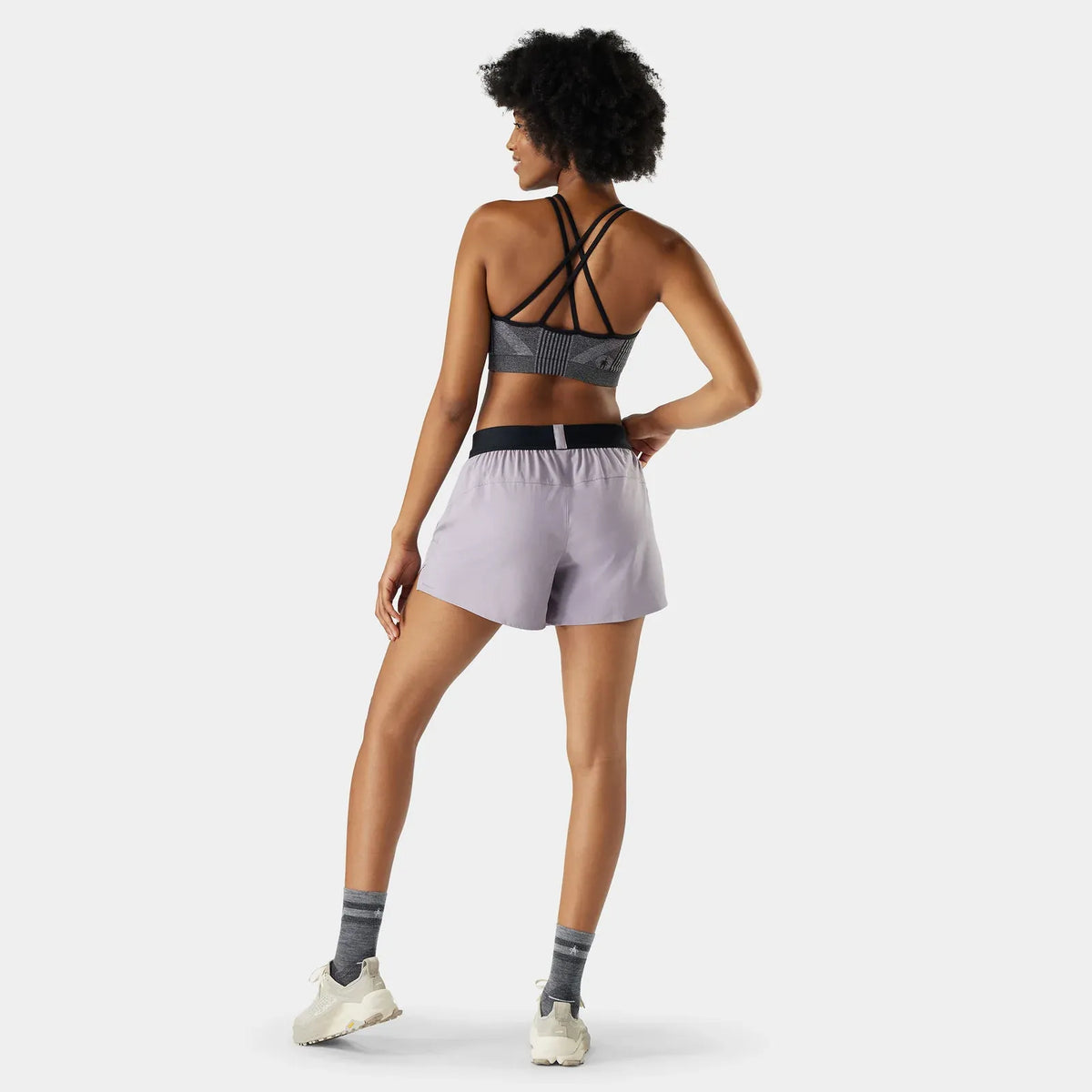 Woman wearing a smartwool sports bra and smartwool shorts on a white background